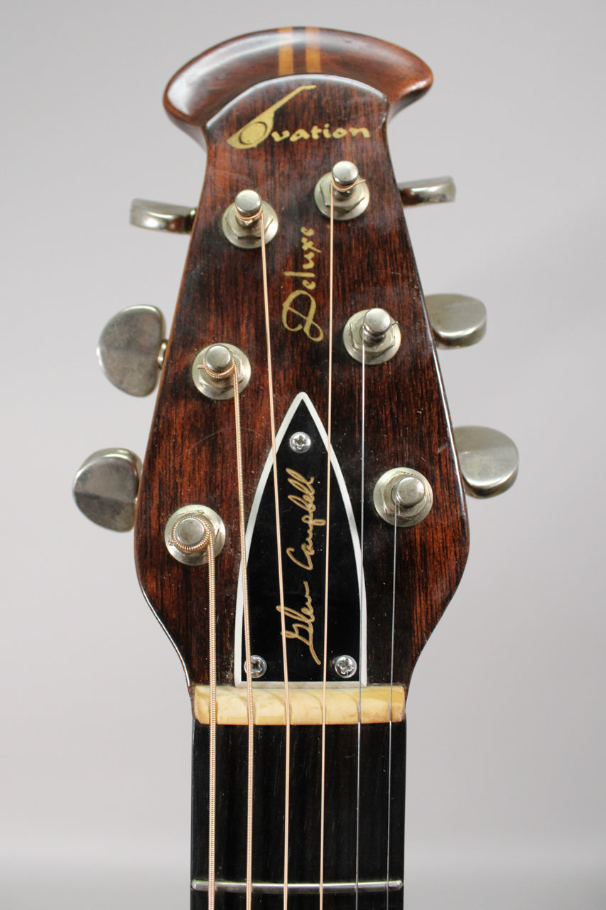 The dark brown headstock, with six silver tuners and a black truss rod cover, shows light wear and a few scratches.