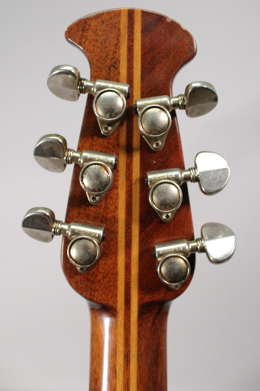 The back of the guitar's headstock, showing six tarnished chrome tuners and a dark wood finish with two lighter wood stripes.