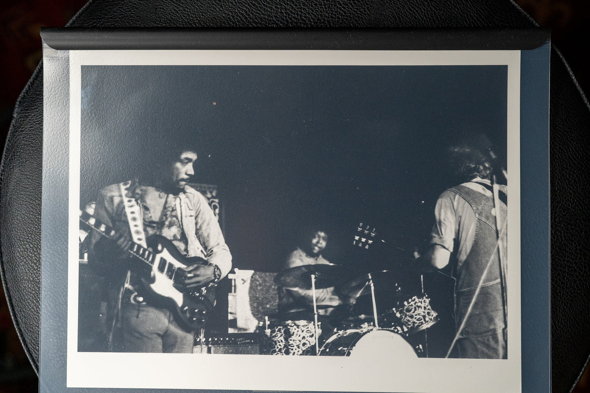 Black and white photo of Jimi Hendrix playing a white SG Custom, with a drummer and another guitarist behind him.