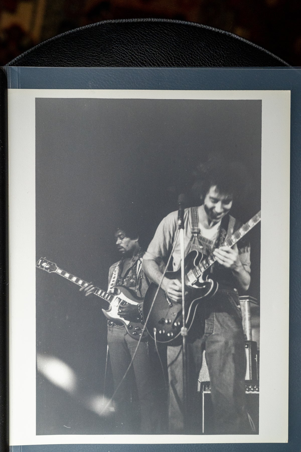 Black and white photo of two musicians on stage, one playing a light-colored SG, the other a dark-colored hollow body.