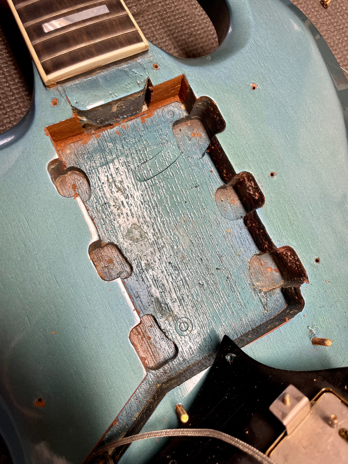 Close-up of the guitar's body, showing the neck joint and pickup cavity with exposed wood and worn Pelham Blue finish.