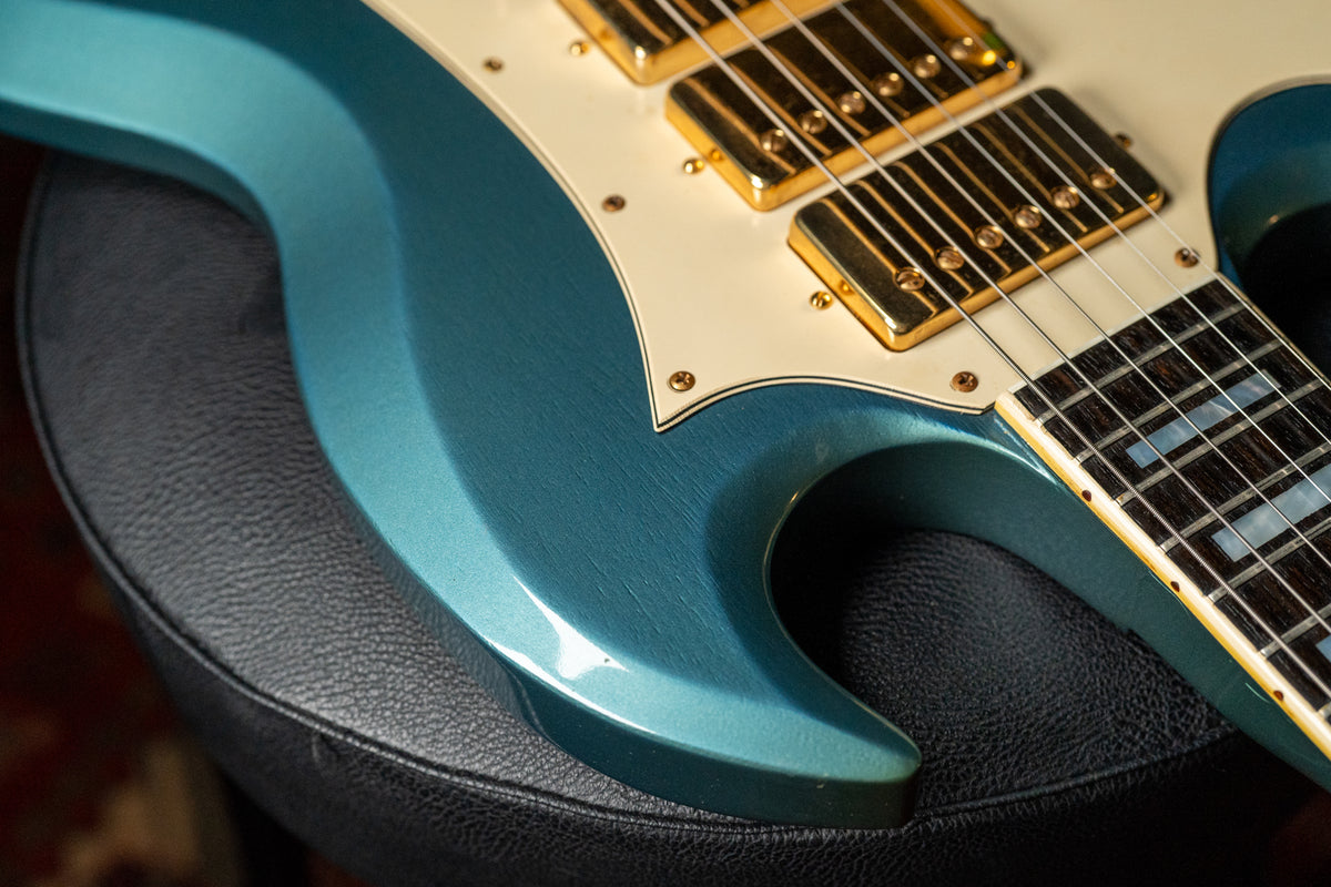 Close-up of the guitar's lower body, showing the metallic Pelham Blue finish with fine checking, cream pickguard, and gold humbuckers.