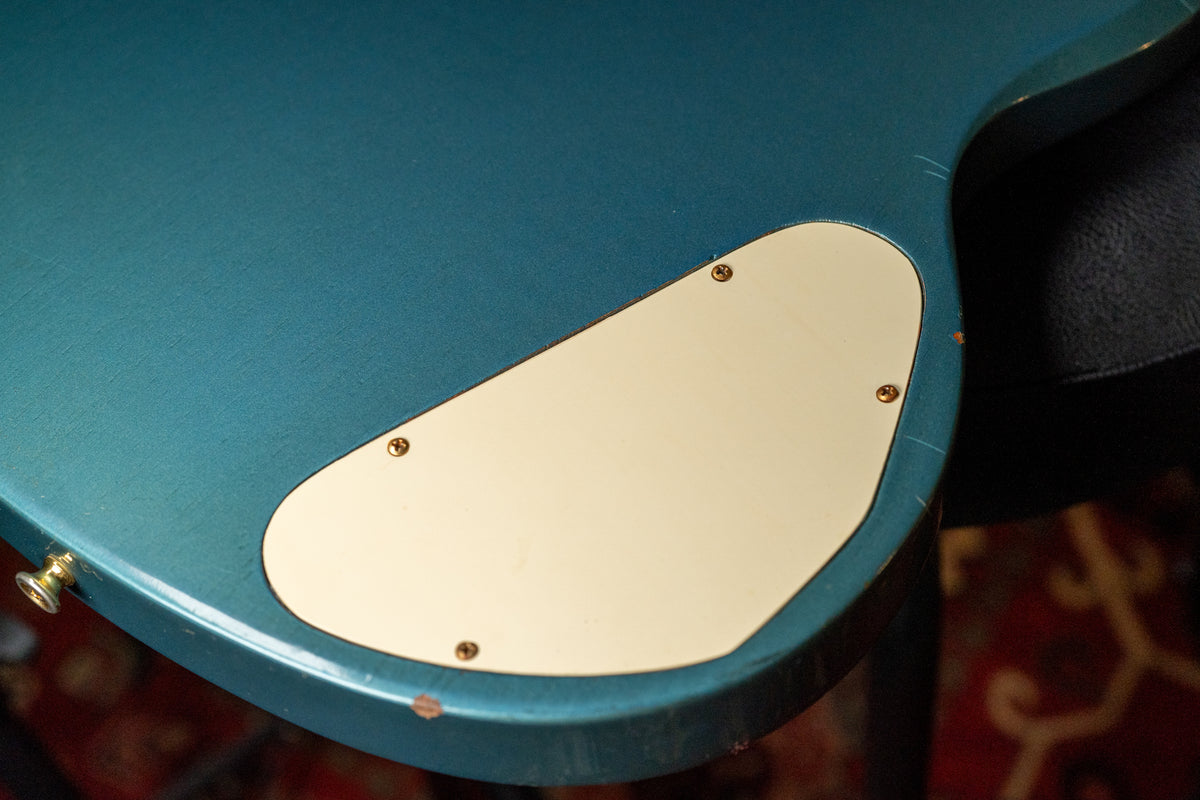 Close-up of the guitar's Pelham Blue back, showing the cream control cavity cover, a gold strap button, and finish wear.