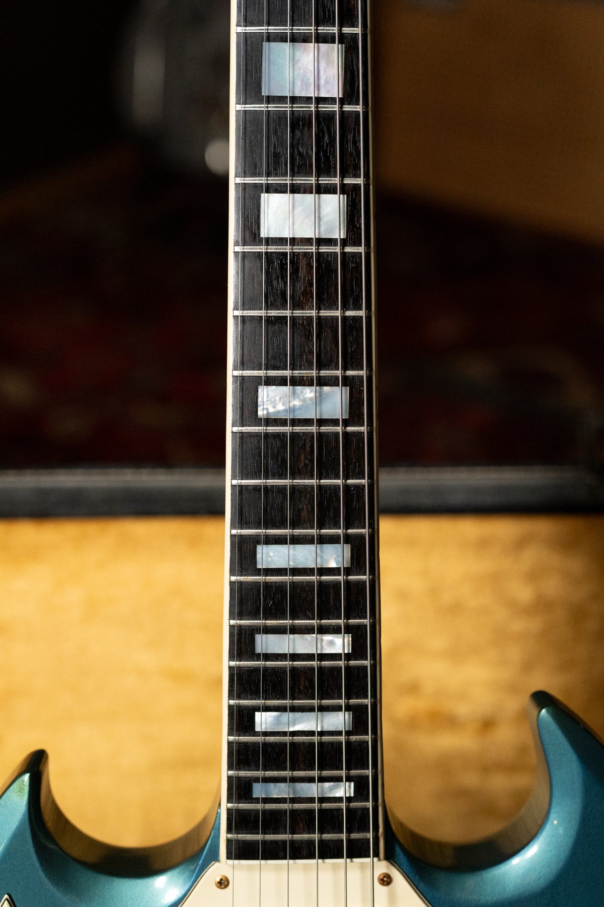 Close-up of the dark fretboard with rectangular mother-of-pearl inlays, showing some fret wear and the Pelham Blue body below.