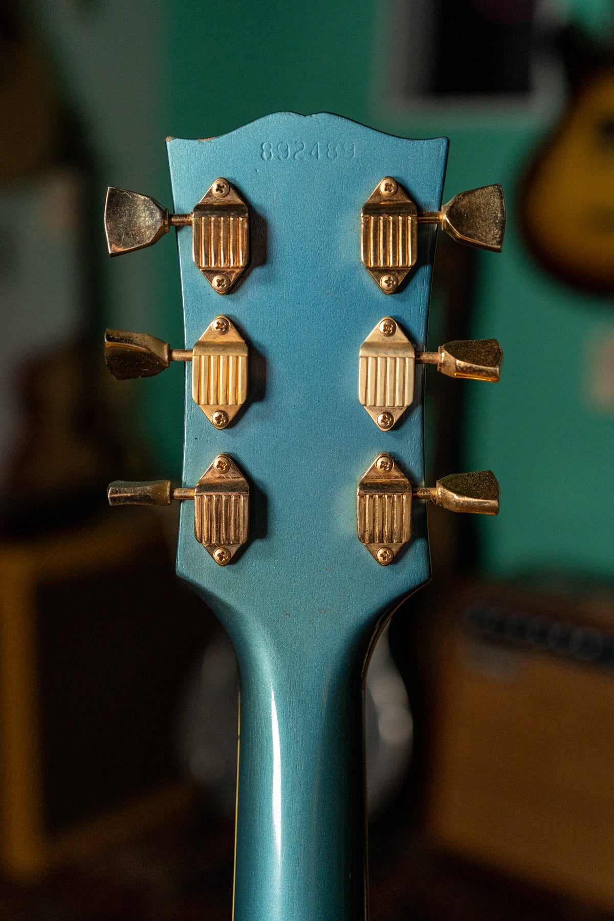 The back of the Pelham Blue headstock and neck, showing six gold tuners with trapezoid buttons and visible wear on the finish.