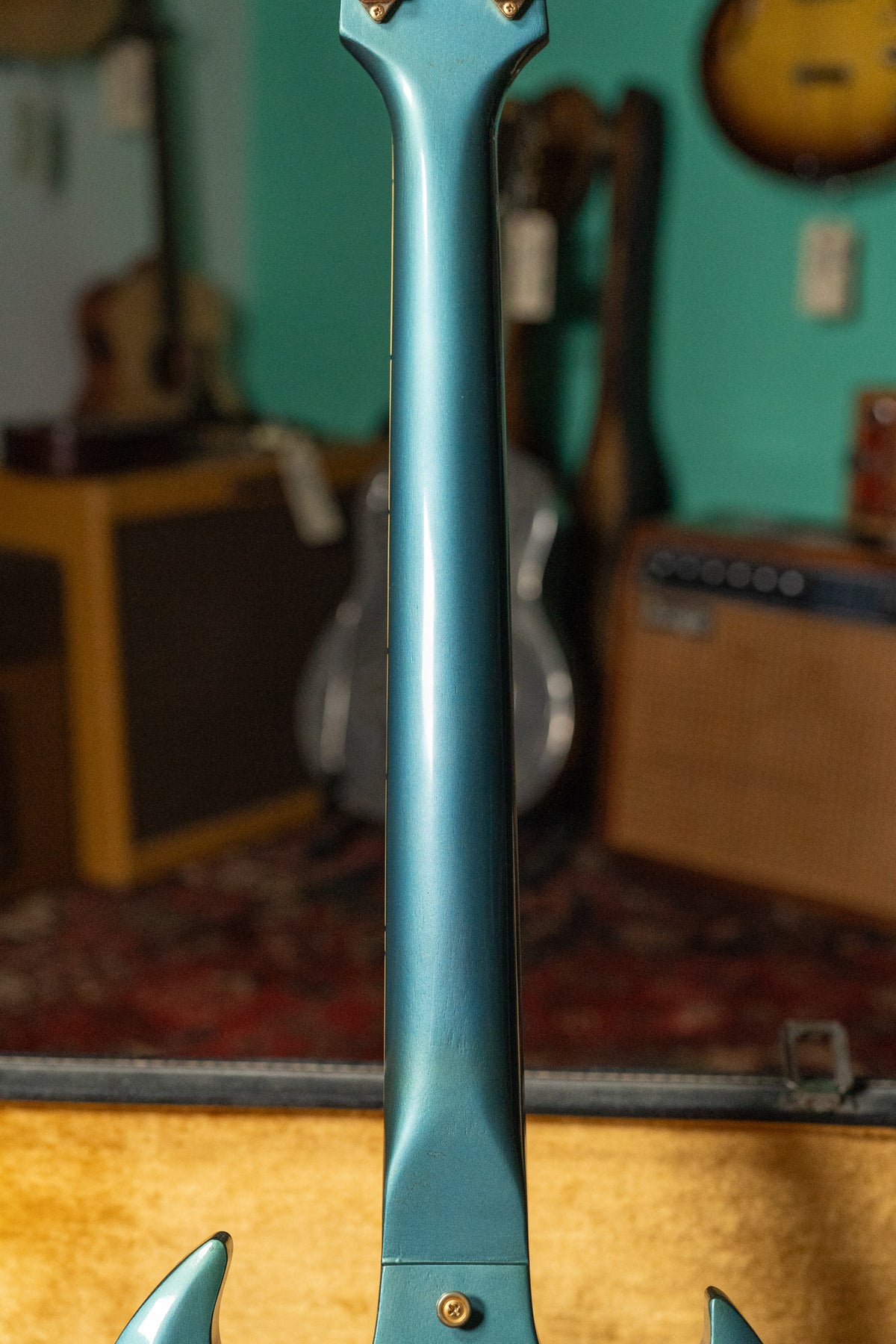 The guitar's Pelham Blue neck and headstock are viewed from behind, showing gold tuning pegs and a shiny, worn finish.