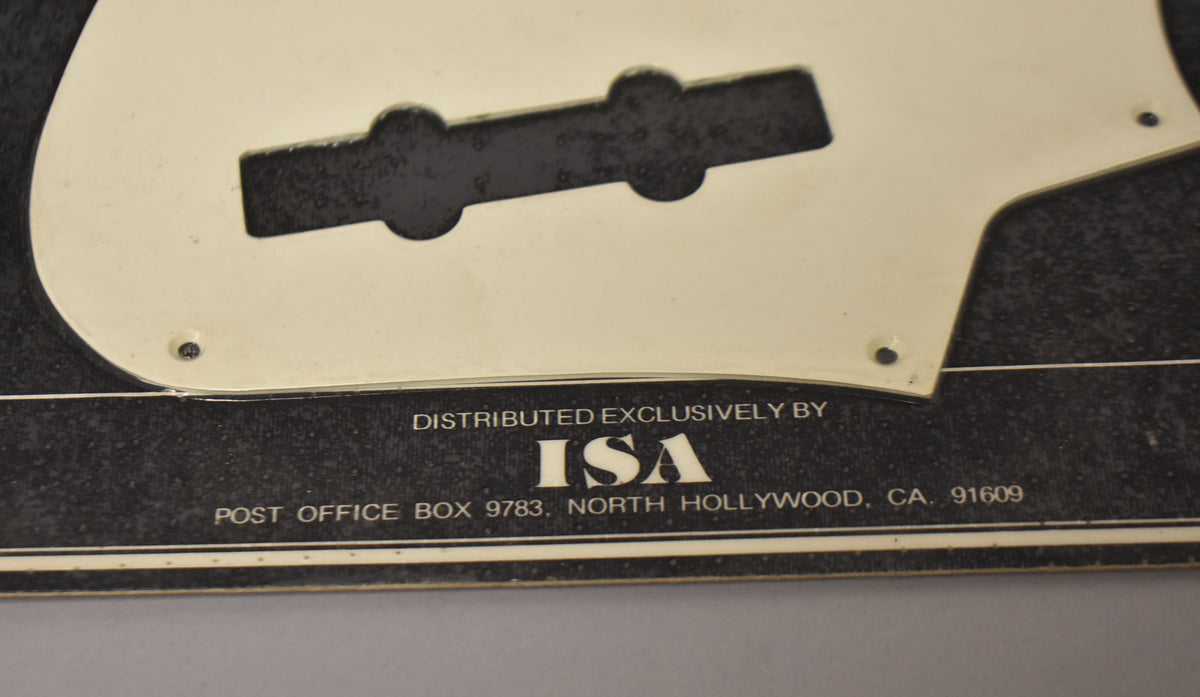 The white pickguard is partially visible, showing a pickup cutout and screw holes, resting on its original black packaging.
