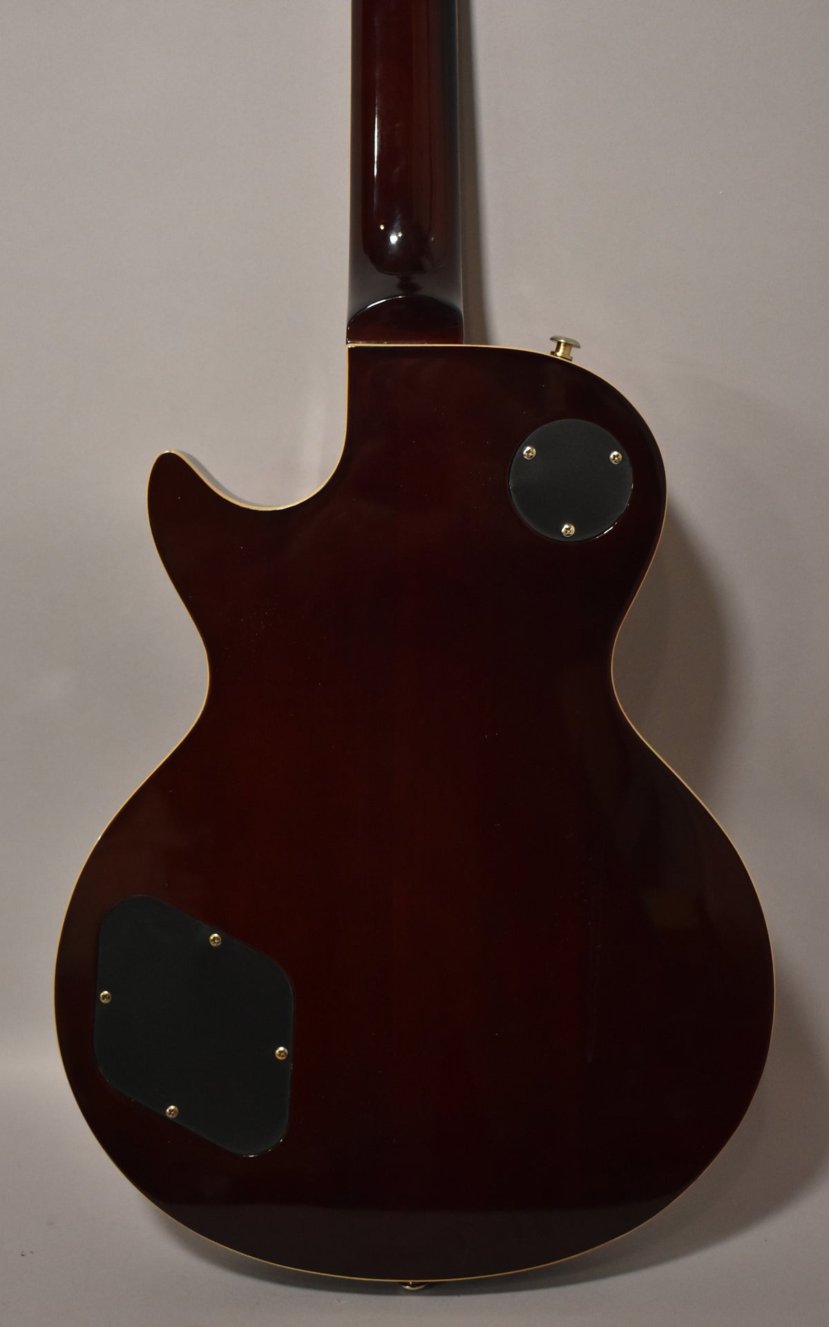 The guitar's dark brown back and neck are visible, with two black control plates and a strap button on the upper bout.