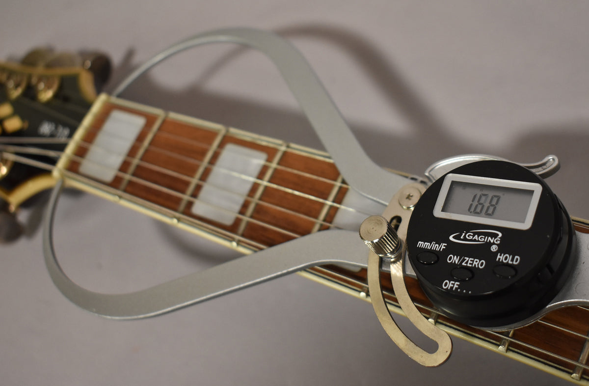Close-up of the guitar's fretboard with block inlays, showing a digital fret height gauge measuring 1.88mm on the frets.