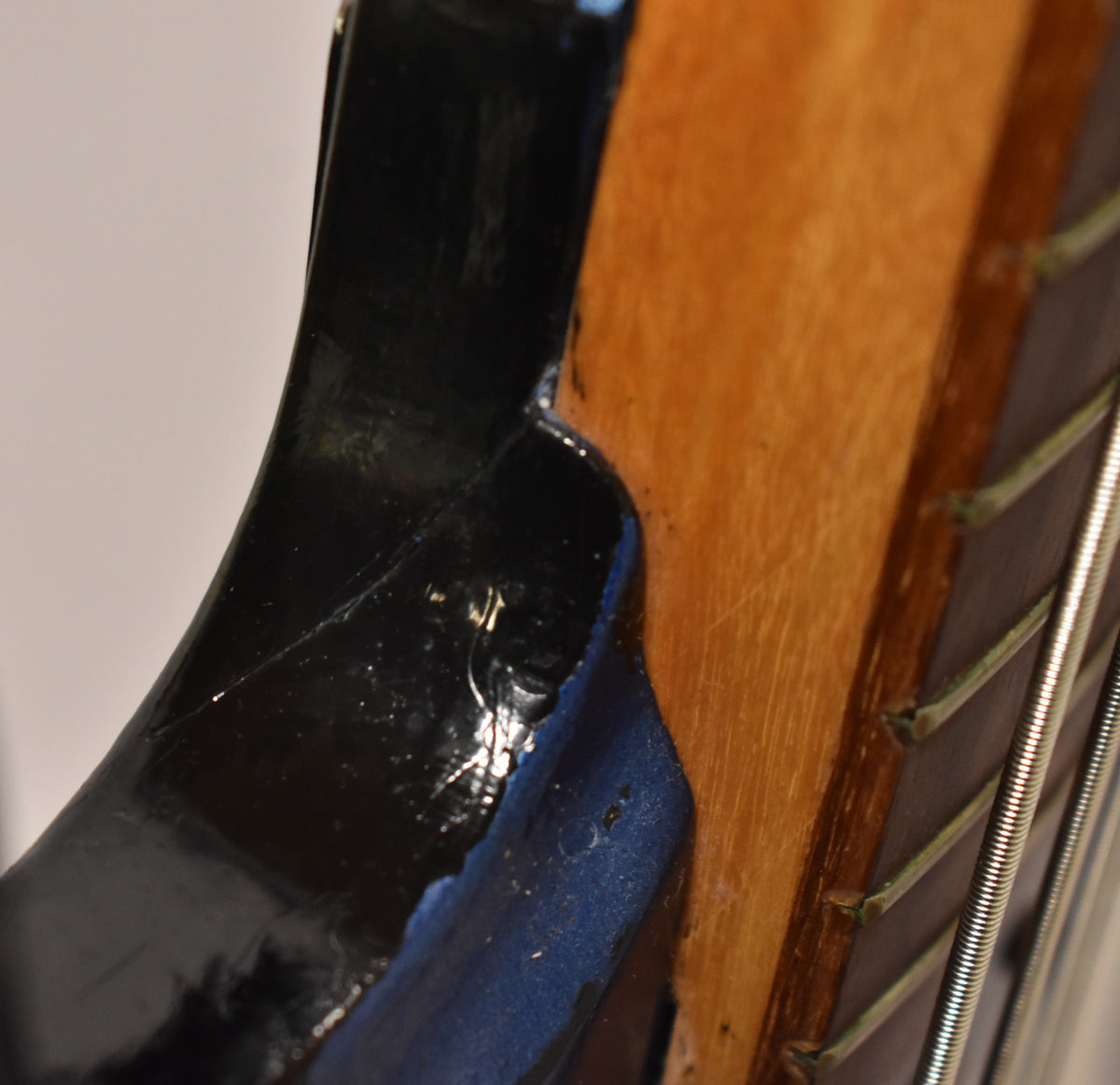 Close-up of the neck joint, showing chipped blue finish revealing black undercoat, and a crack in the finish on the body.