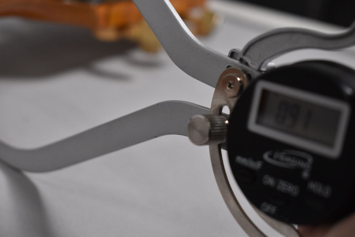 A digital caliper shows a reading of 0.91, with a blurred orange object in the background.