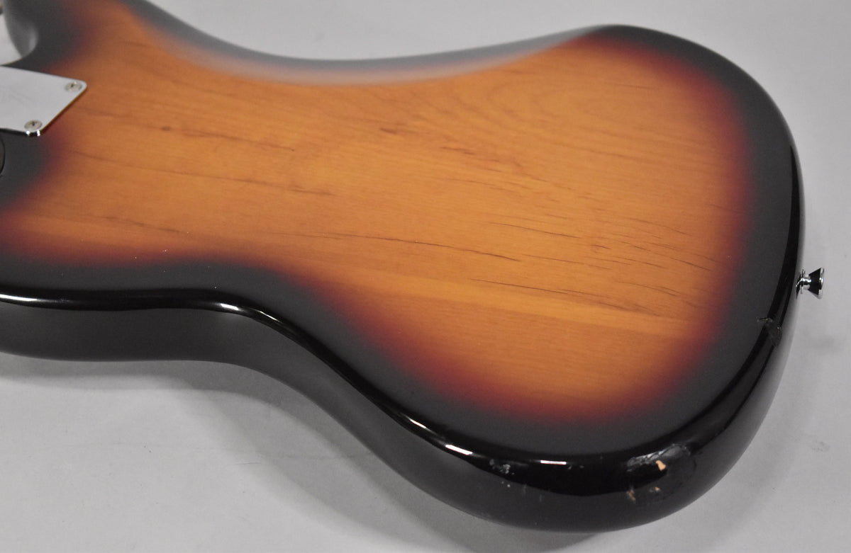 The guitar's back shows a 3-tone sunburst finish with visible wood grain, light scratches, and a chip on the lower bout near the strap button.
