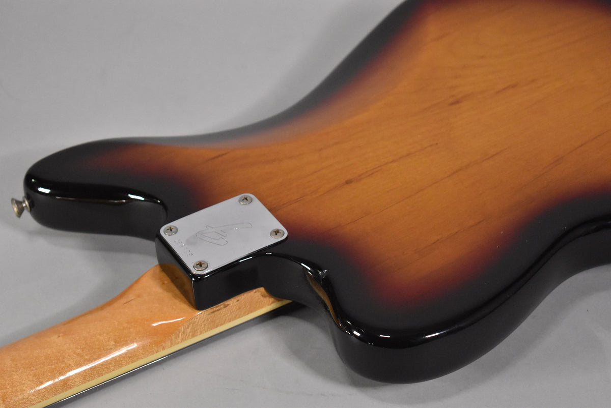Rear view of a 3-tone sunburst electric guitar body, showing the neck joint and chrome neck plate with a faint logo and light wear.