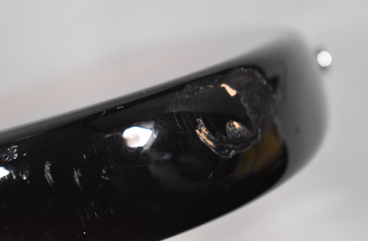 Close-up of the guitar's black body edge, showing significant paint chips revealing lighter wood, and fine finish checking.