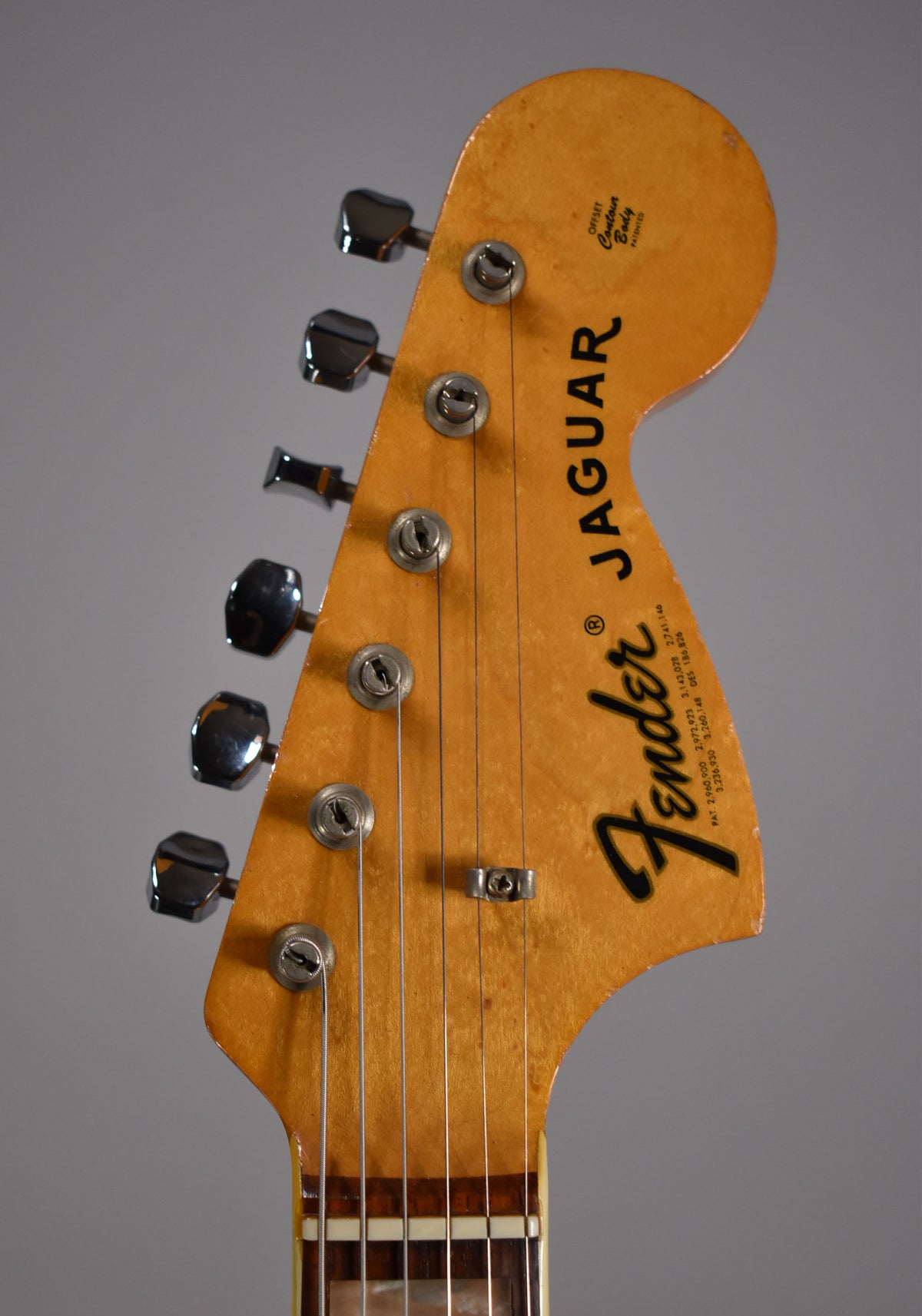 Close-up of the headstock, showing six chrome tuners, a string tree, and a worn, ambered finish with light checking.