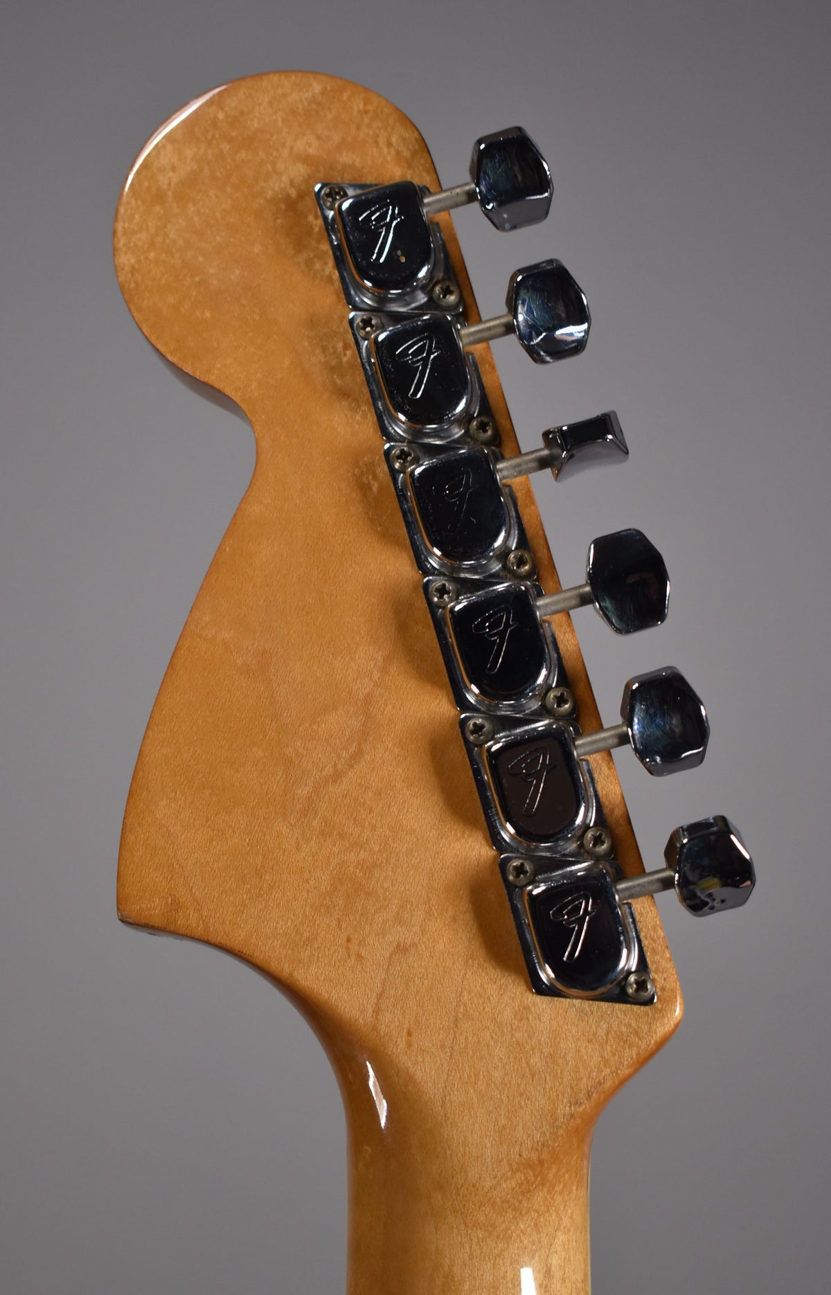 The back of the headstock and top of the neck, showing six chrome tuners with some tarnishing and a few small dings on the wood.