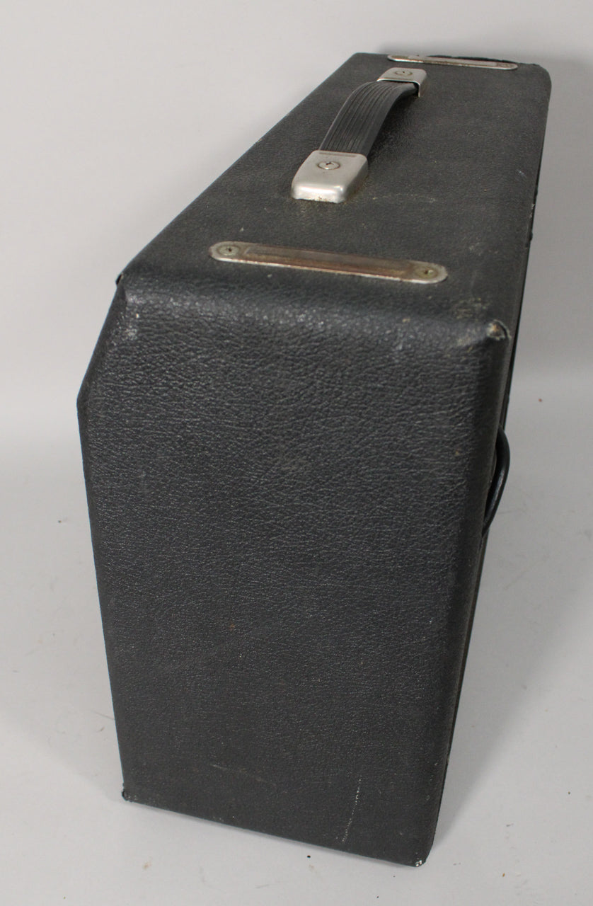 The black textured amp head is viewed from above, showing its top handle and worn metal feet, with scuffs on the corners.