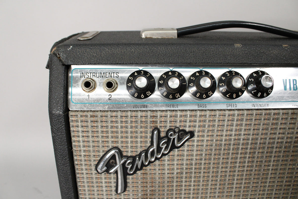 Close-up of the amp's top left, showing two input jacks, five black control knobs, and a silver grille cloth with a black logo.