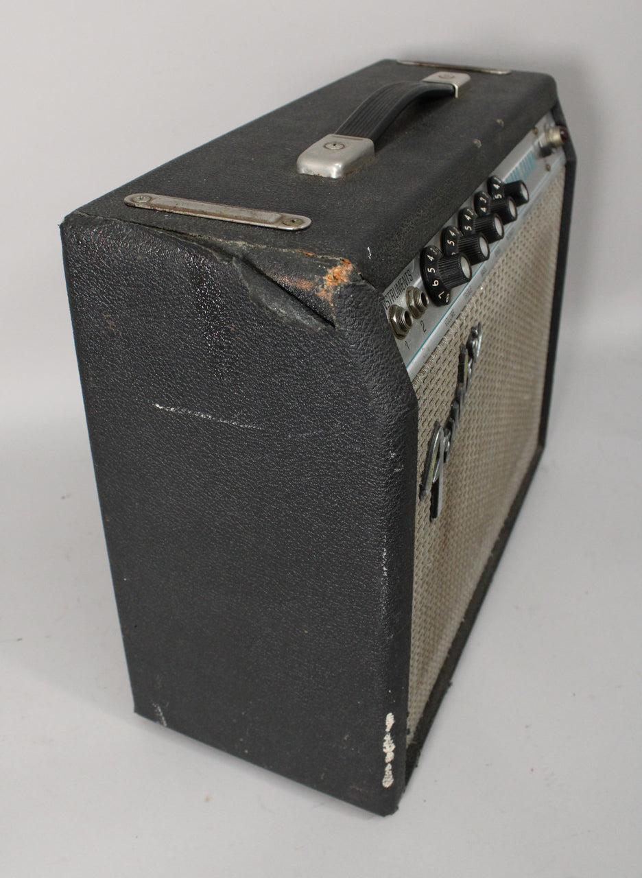 The black tolex combo amp is angled, showing the worn top handle, silver control panel with black knobs, and light gray grille cloth.