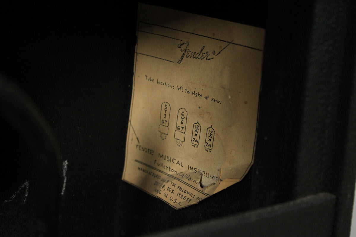 A close-up of the amp's interior reveals a faded, creased tube chart with diagrams and text, partially peeling from the black cabinet.