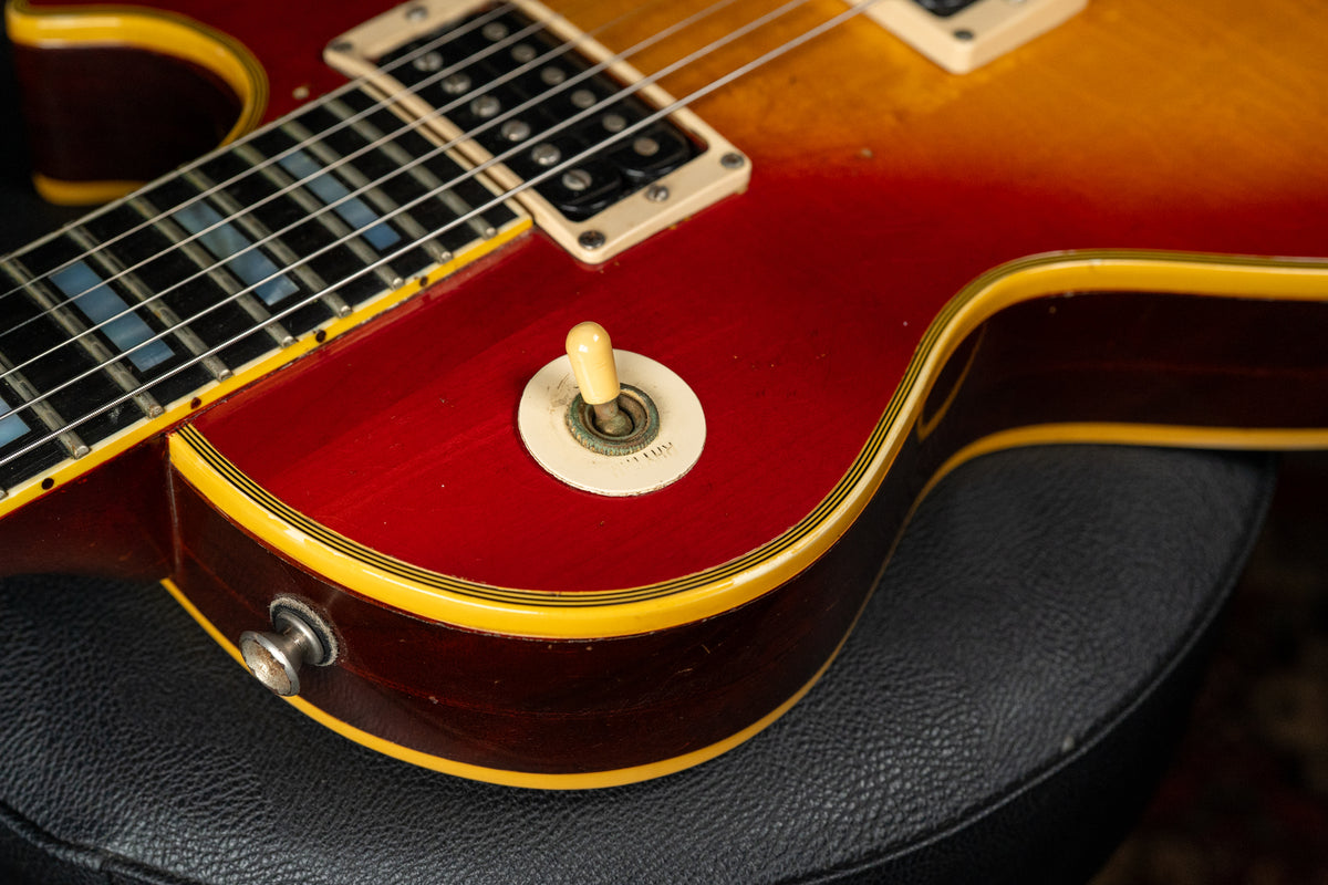 Close-up of the cherry sunburst body, showing the pickup selector switch, output jack, and binding with visible wear and checking.