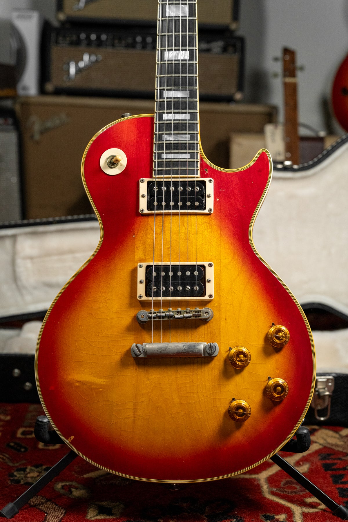 Cherry sunburst guitar, angled from the neck to the lower bout, showing two humbuckers, four gold knobs, and finish checking.
