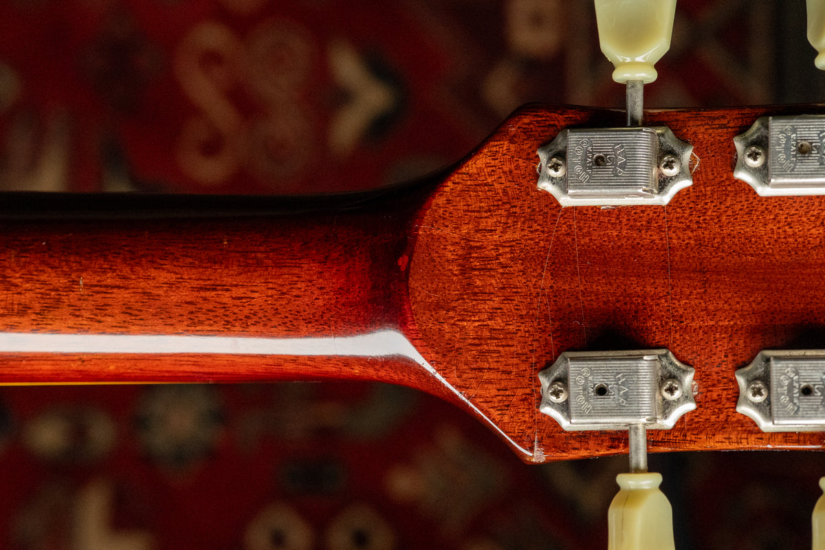 Rear view of the guitar's headstock and neck heel, showing the cherry sunburst finish, cream tuning pegs, and light finish checking.