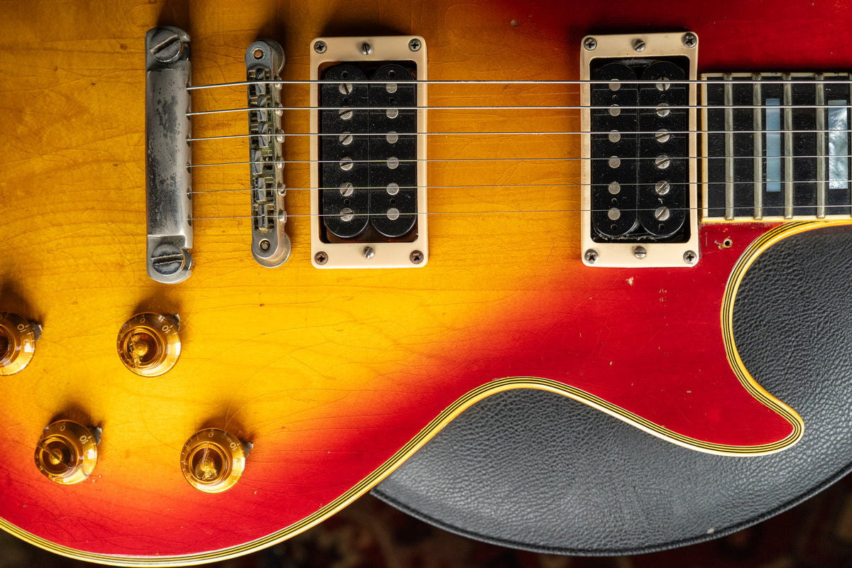 Close-up of the cherry sunburst body, showing the bridge, two humbucker pickups with cream surrounds, four gold control knobs, and pickguard.