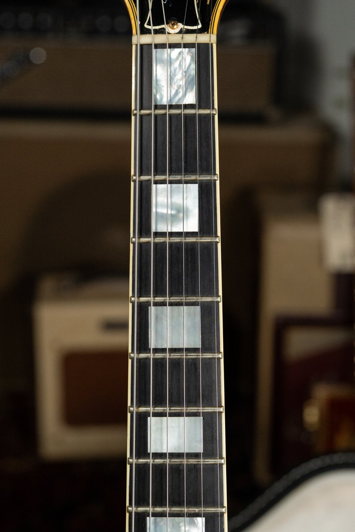 Close-up of the dark fretboard with rectangular mother-of-pearl inlays, showing light wear on the frets and binding.