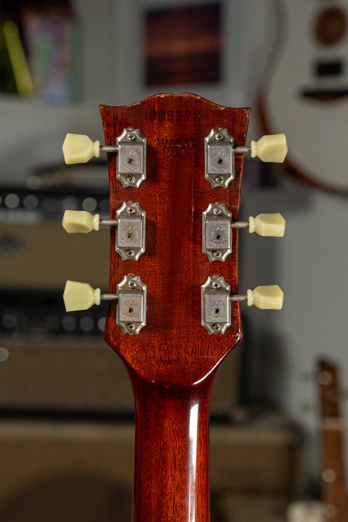 Rear view of the cherry sunburst headstock and upper neck, showing six cream tuning pegs, chrome tuners, and finish wear.