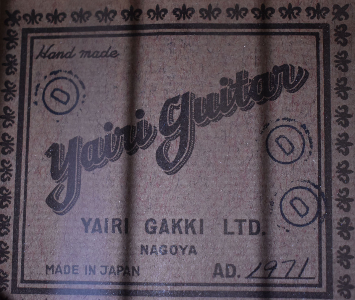 Close-up of the guitar's internal label, a brown paper rectangle with black text and a decorative border, showing "AD. 1971" handwritten.