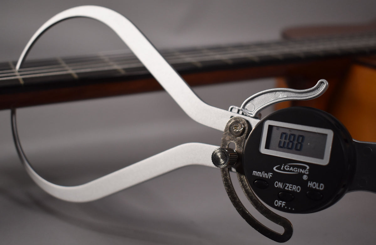A digital caliper measures the string height at the 12th fret of the classical guitar, displaying "0.88".
