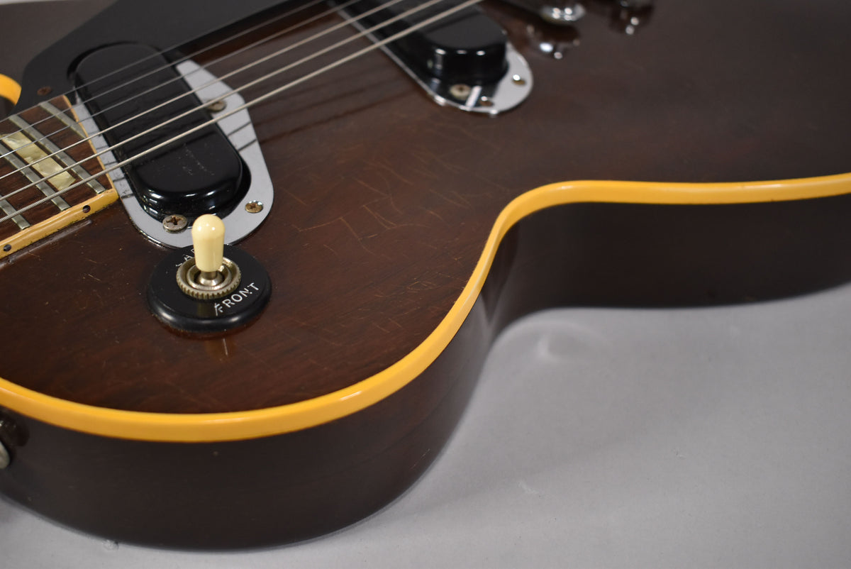 Close-up of the dark walnut body, showing a cream pickup selector switch, a black humbucker, and light scratches on the finish.