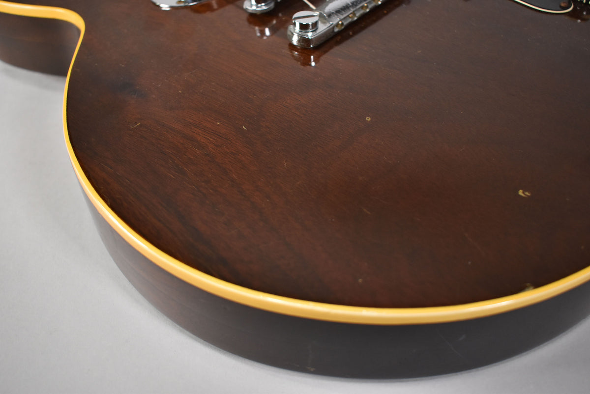 Close-up of the dark walnut body, showing the lower bout with cream binding, a few small dings, and light surface scratches.