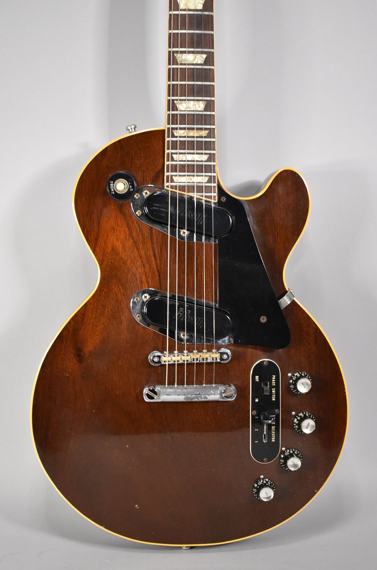 Full body shot of a dark walnut Les Paul with a glossy finish, showing two humbuckers, a black pickguard, and four control knobs.