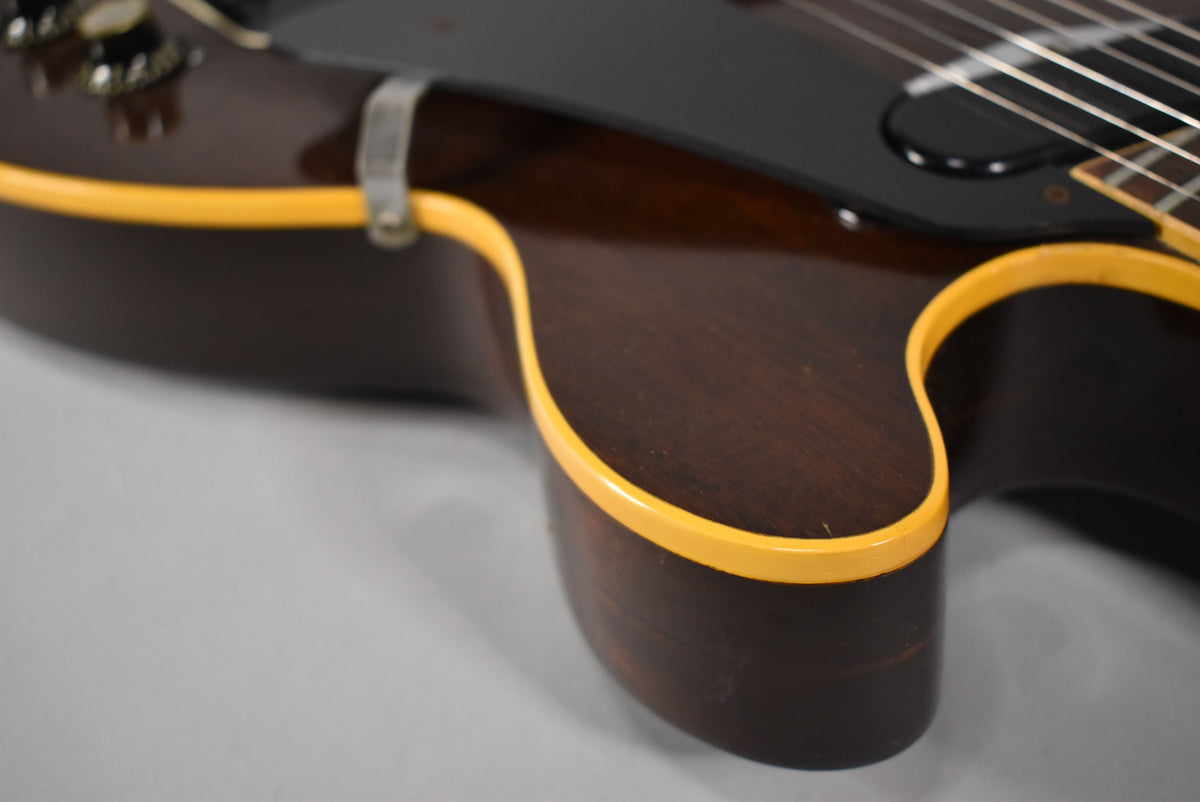 Close-up of the guitar's lower bout, showing the dark walnut finish, cream binding, and some light wear on the body.