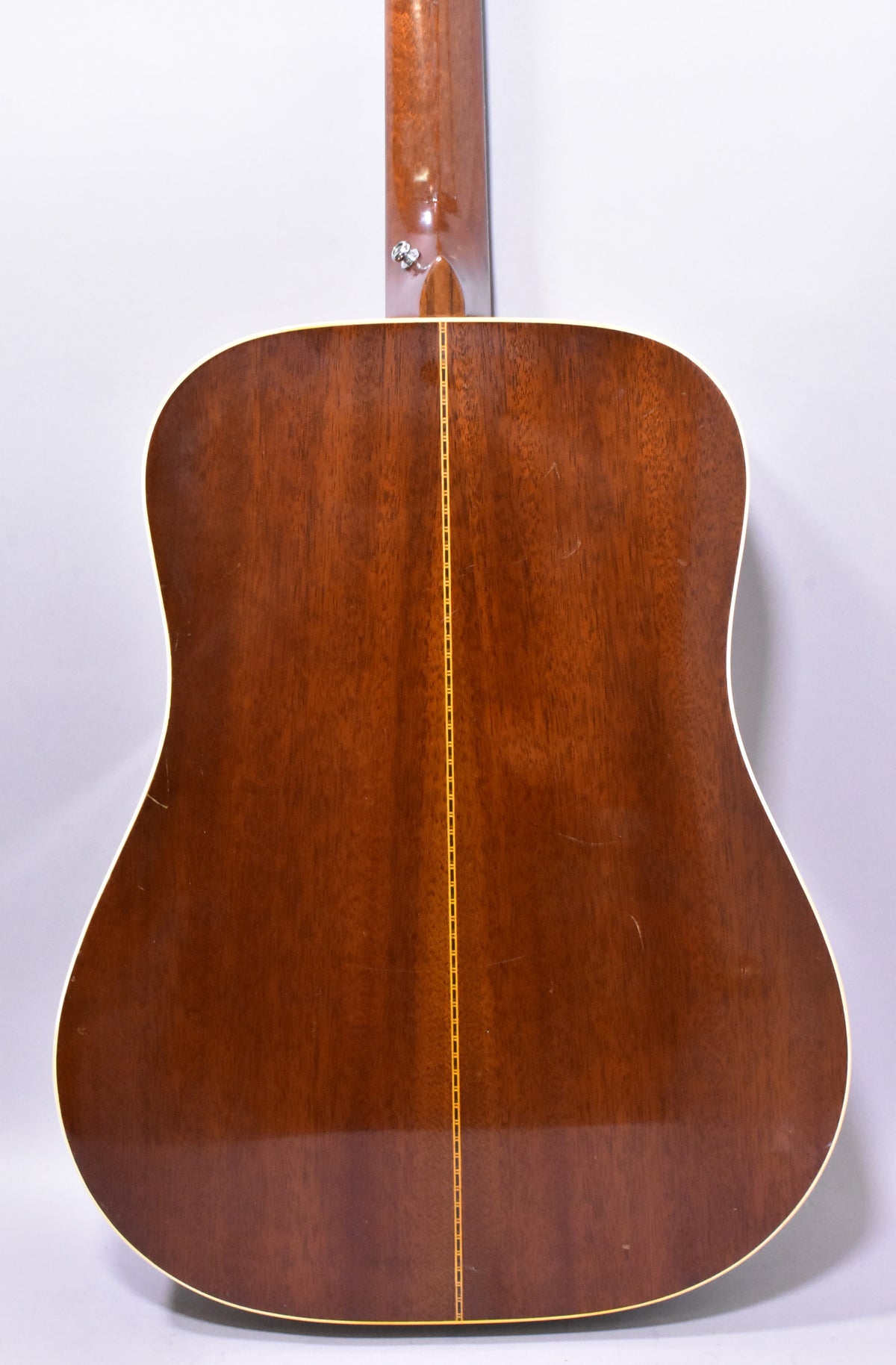 The guitar's dark brown back and neck are visible, with a light-colored binding and a decorative stripe down the center.