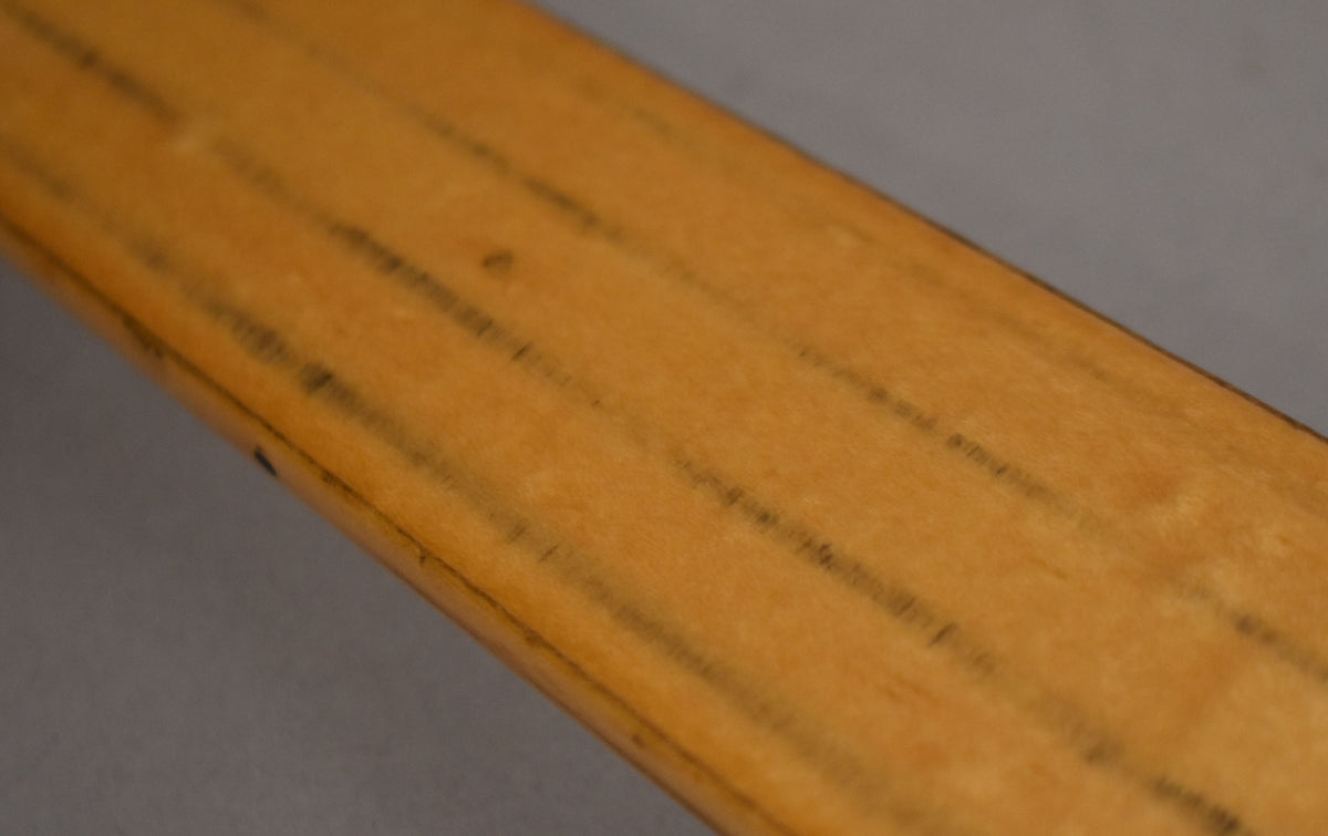 Close-up of the maple fretless neck, showing dark lines where frets would be, and some wear along the lower edge.