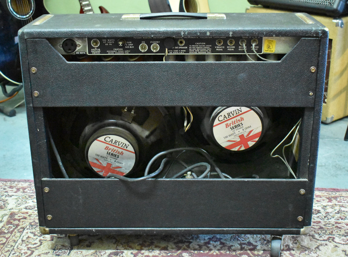 Rear view of the black combo amp, showing two Carvin British Series 12-inch speakers, exposed tubes, and various input/output jacks.