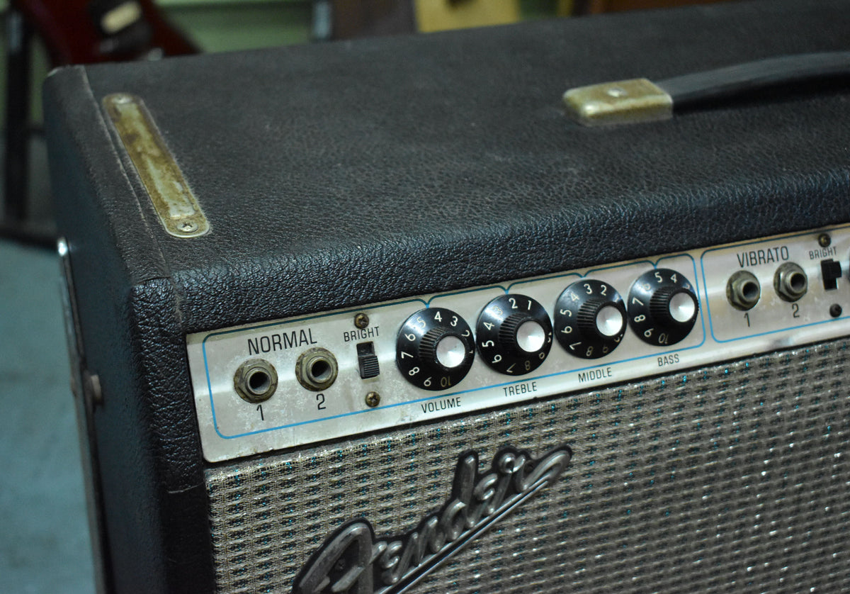 Close-up of the black textured top and silverface control panel, showing worn handle hardware, input jacks, switches, and black numbered knobs.