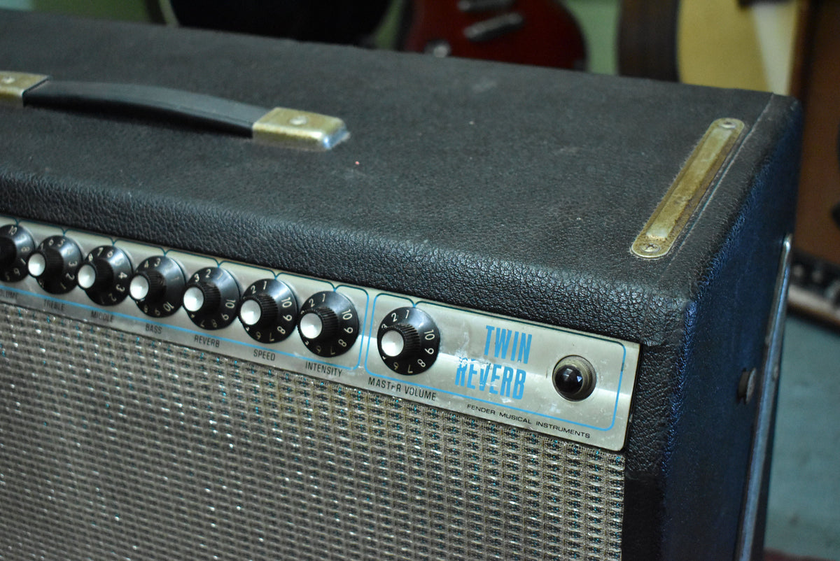 Close-up of the amp's black textured top and silverface control panel with black numbered knobs, showing a worn handle and corner protector.