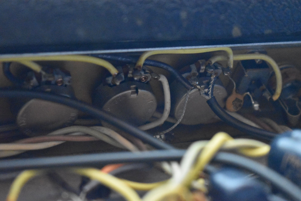 Close-up of the amplifier's internal wiring, showing several grey potentiometers connected by yellow, white, and black wires.