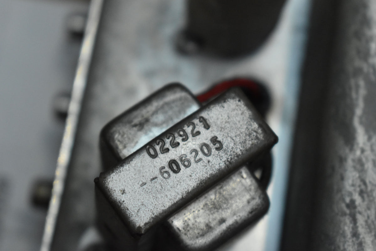 Close-up of a silver-grey metal component with stamped numbers "022921" and "--606205", showing some surface wear.