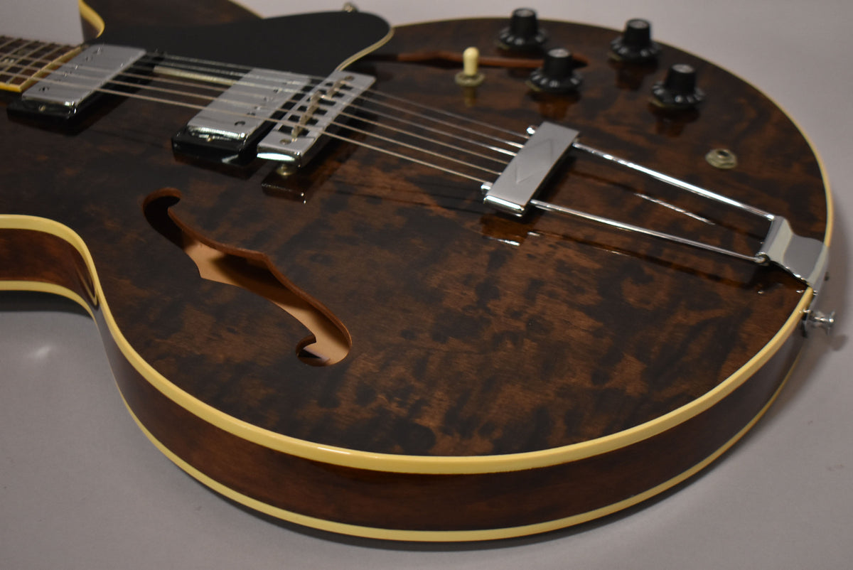 Close-up of the guitar's lower body, showing the dark walnut finish with prominent wood grain, f-hole, and chrome hardware.