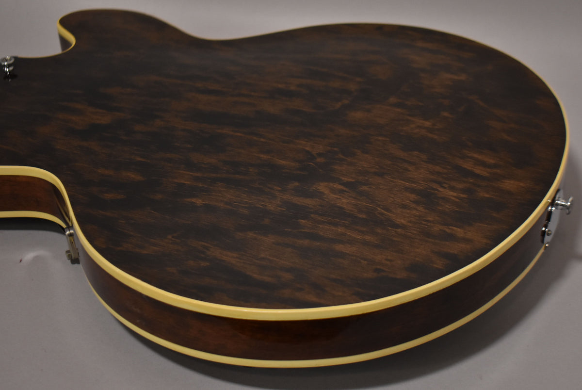 The guitar's dark walnut back and sides are visible, with cream binding and some light surface wear on the body.