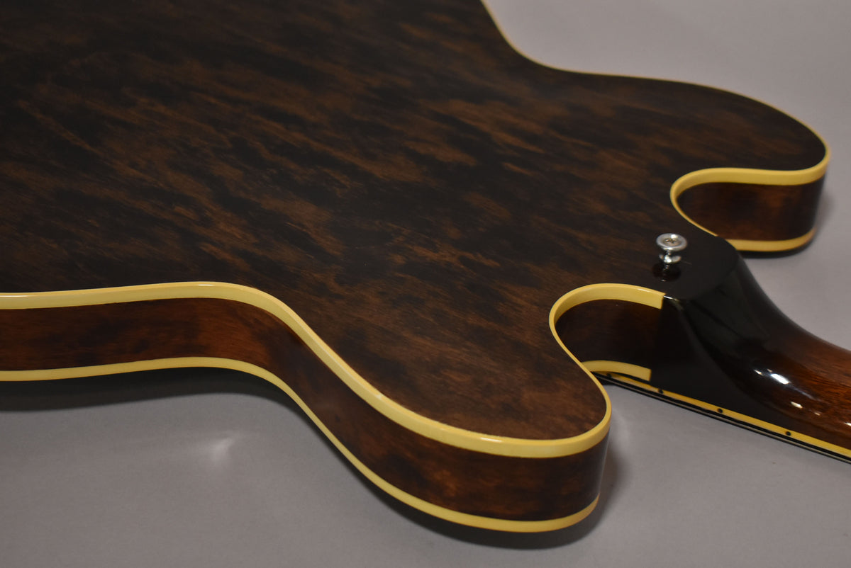 Close-up of the guitar's dark walnut back, showing the lower bout, cutaway, and neck heel with a strap button.