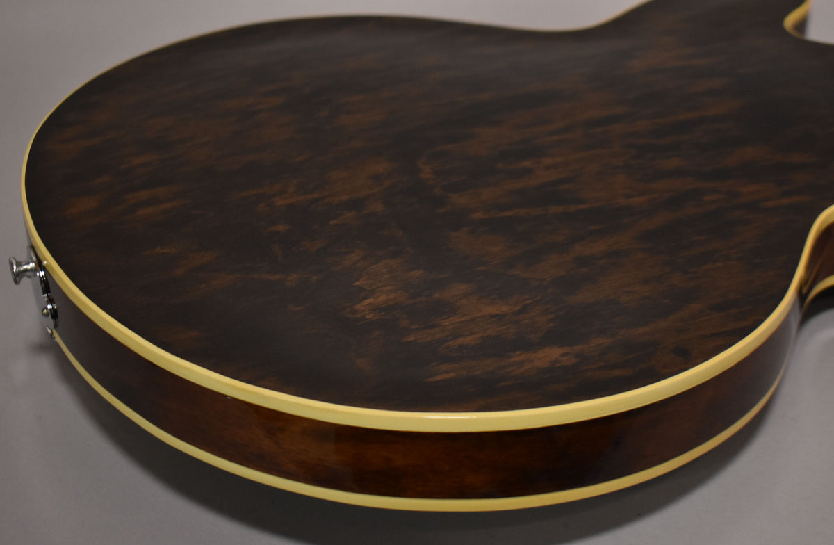 Close-up of the guitar's lower bout, showing the dark walnut finish with visible wood grain and cream binding along the body edge.