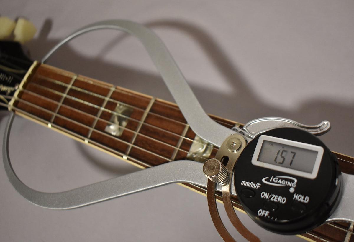 Close-up of the guitar's fretboard with a digital caliper measuring the nut width at 1.57 inches.