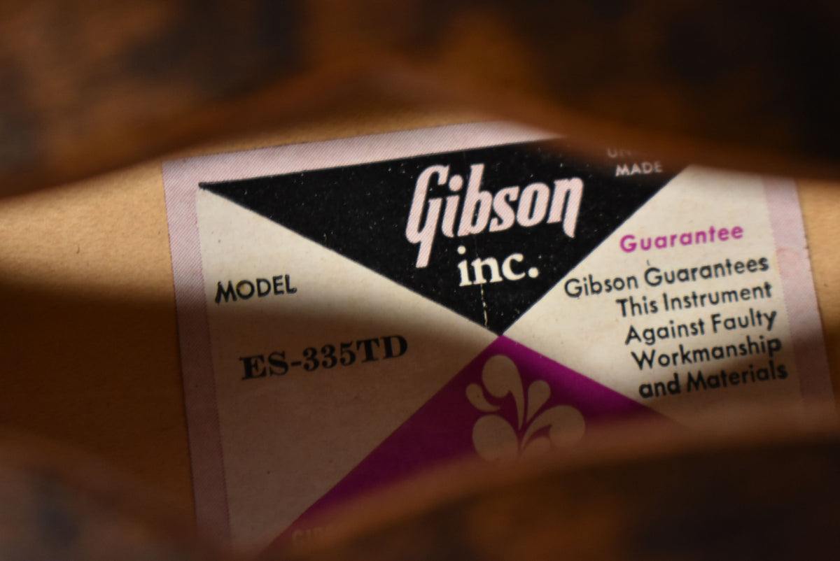Close-up of the guitar's interior label, showing "MODEL ES-335TD" and a "Gibson inc." logo with a guarantee.