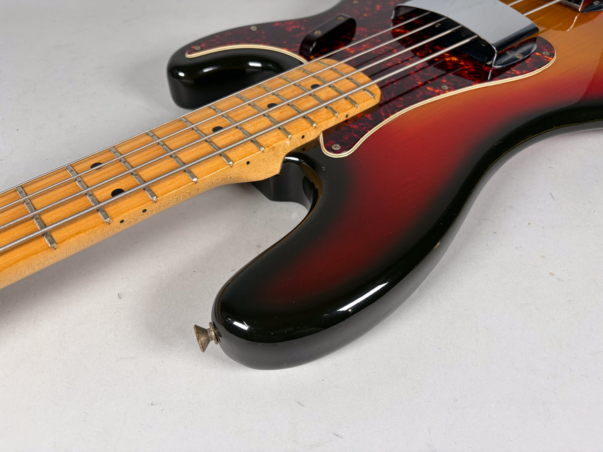 Close-up of the bass body and neck, showing the sunburst finish, tortoise pickguard, chrome pickup cover, and maple fretboard.